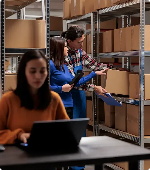 Warehouse managers tracking inventory on a tablet and laptop, utilizing small business funding options.